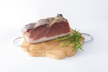 Tasty Italian Speck on wooden cutting board. White background. There is also rosemary