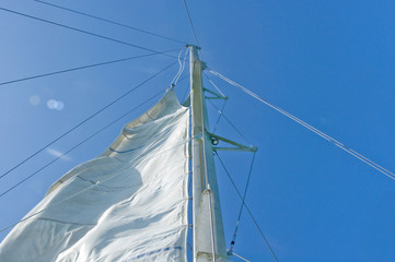 white yacht sails against the blue sky of tropical