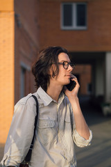 Handsome young man talking on the smartphone in the city, in front of modern building.
