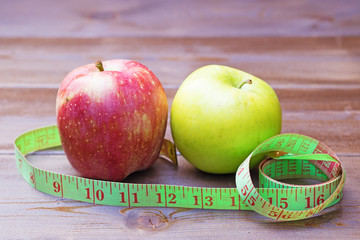 Green and red apples wrapped with measuring tape
