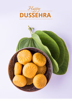 greeting card saying happy vijayadashmi or happy dussehra, indian festival dussehra, showing apta leaf or Bauhinia racemosa with traditional indian sweets pedha in silver bowl
