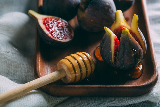 Close up of fresh figs with honey dipper on wooden tray