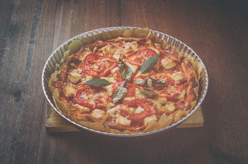 Pizza in metal plate on wood table. Vintage toning