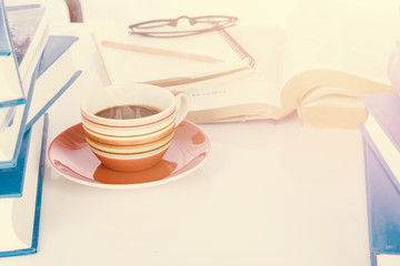 Cup of coffee on book with Eyeglasses book stack background