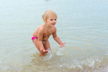 Adorable toddler girl playing with beach toys on white sand beach