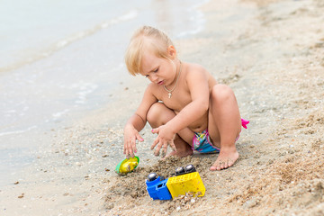 Adorable toddler girl playing with beach toys on white sand beach