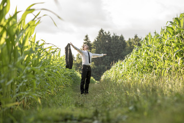 Person in necktie standing in between rows of corn © Gajus