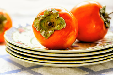 Persimmons on a plate in sunlight. Close up detail 