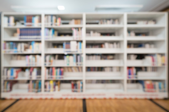 Blurred background of public library, bookshelf with books, education concept