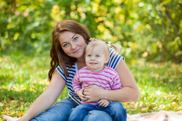 Mom and daughter in the same clothes for a walk in the park in autumn