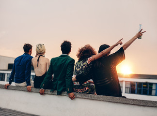 Friends enjoying drinks on rooftop at sunset