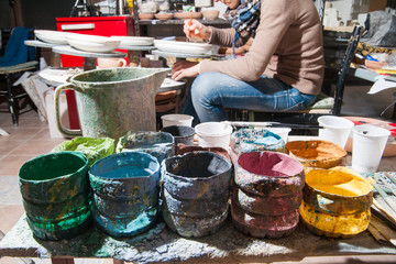 Pottery decorating: work table of a pottery decorator of Caltagirone with different color containers