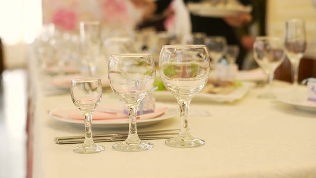 Three glasses on table at restaurant and waiters at background