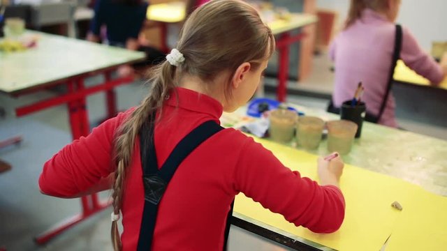 The girl draws a picture paints in classroom