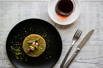 Turkish Dessert irmik helvasi with pistachio powder and tea.