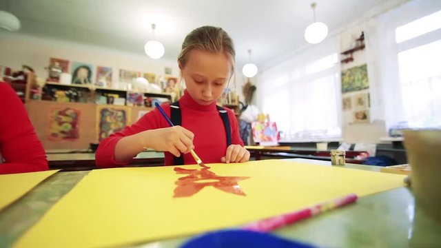 The girl draws a picture paints in classroom