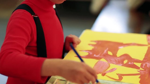 The girl draws a picture paints in classroom