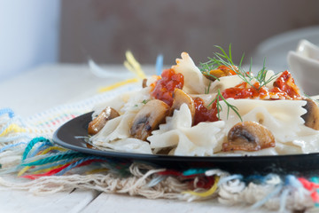 Farfalle Pasta with mushrooms on white plate and tomato sauce