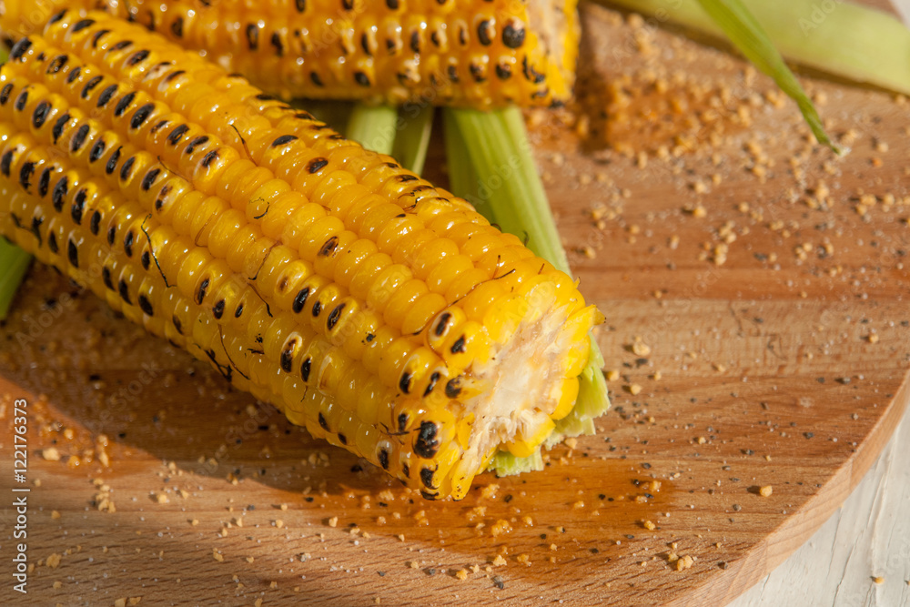 Poster two grilled corn on a wooden plate