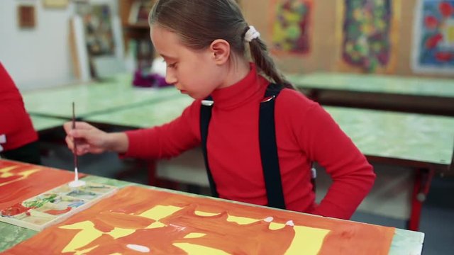 The girl draws a picture paints in classroom