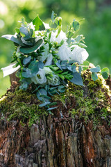 Wedding bouquet of white flowers on the wood stump outdoors , close view