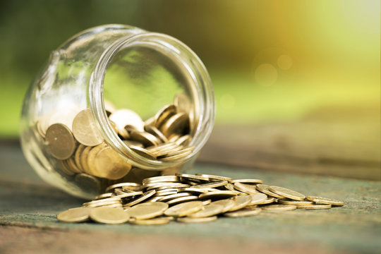 Golden money coins in a glass jar - charity, donation concept