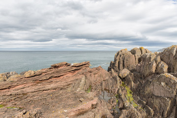 Fototapeta na wymiar James Hutton's famous angular unconformity at Siccar Point in Berwickshire, Scotland. Gently dipping Devonian sandstone overlying near-vertical Silurian greywacke.