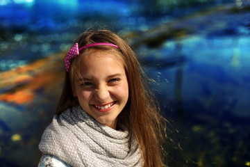 Portret radosnej dziewczynki nad błękitną rzeką.