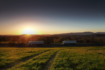 White two truck driving through autumn landscape at sunset 