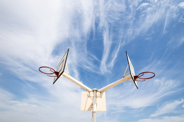 double basketball Hoop against the bright cloudy sky