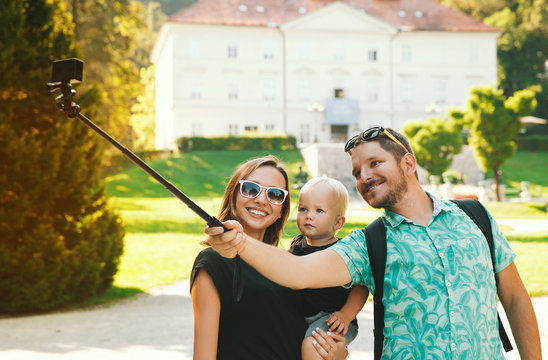 Young family with toddler child making selfie photo on motion camera in park of Europe 
