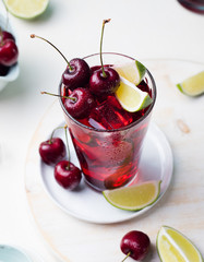 Cherry Limeade, lemonade, cola, cocktail in a tall glass on white, turquoise background Copy space