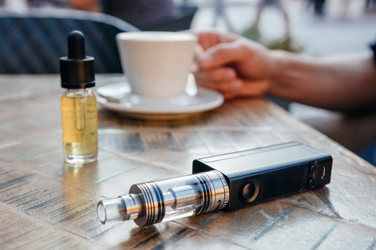 man using vape or electronic cigarette and drinking coffee