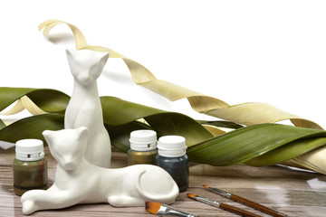 Gypsum white cat's figurine on wooden background - materials and tools for painting