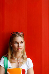 Student with headphones on background blank red Wall