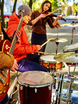 Music street performers with girl violinist on autumn outdoor.