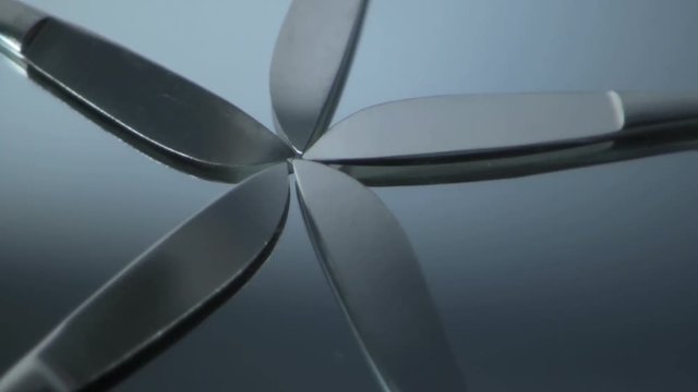 Five scalpels fanned out rotating counterclockwise on a glass mirror. HD 1080.