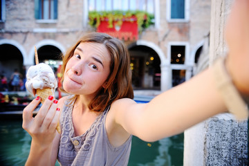 Obraz premium Female traveler making selfie photo with traditional italian ice cream in Venice