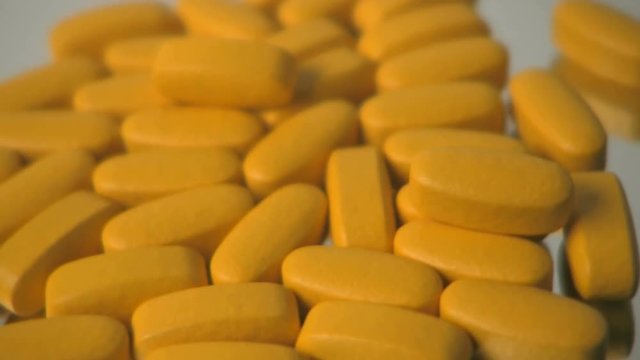 A extreme close up of large yellow vitamins, rotating on turntable. HD 1080.