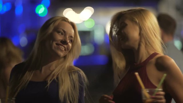 Beautiful blonde girls dancing at party, laughing and having fun in nightclub