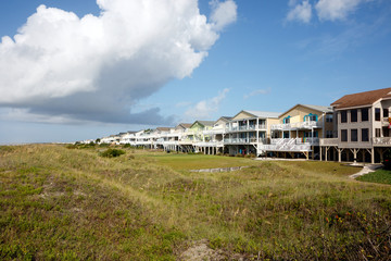 Fototapeta na wymiar Wide angle view of luxury vacation beach rental houses along the green sand dunes; Sunset Beach, North Carolina