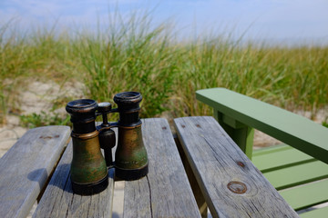 Naklejka premium A Pair of Vintage Binoculars sitting on Wooden Table at Beach Sea Shore