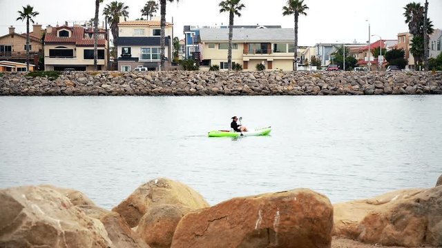 A lone kayaker paddles along the harbor for fun.