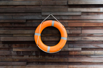 orange lifeguard hanging with rope on wooden wall