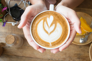 Woman holding hot cup of coffee, with heart shape