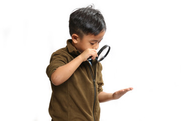 Asian boy using a hand magnifying glass on a white background.