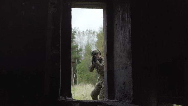 Two military pass through the door of the building the stairs. The soldiers attacked the building. airsoft game