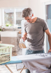 man ironing his shirts at home