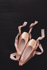 Pink ballet pointe shoes on black wood background