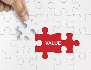 Fototapeta premium Hand holding piece of puzzle with word VALUE